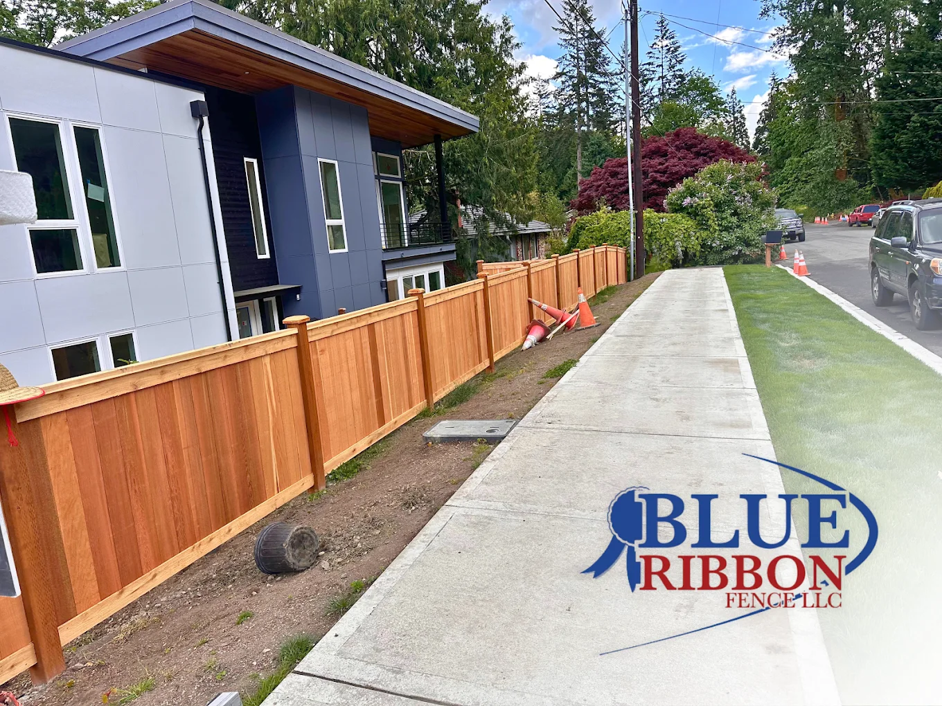 Blue Ribbon wood privacy fence alongside a modern home, with the company logo on the photograph.